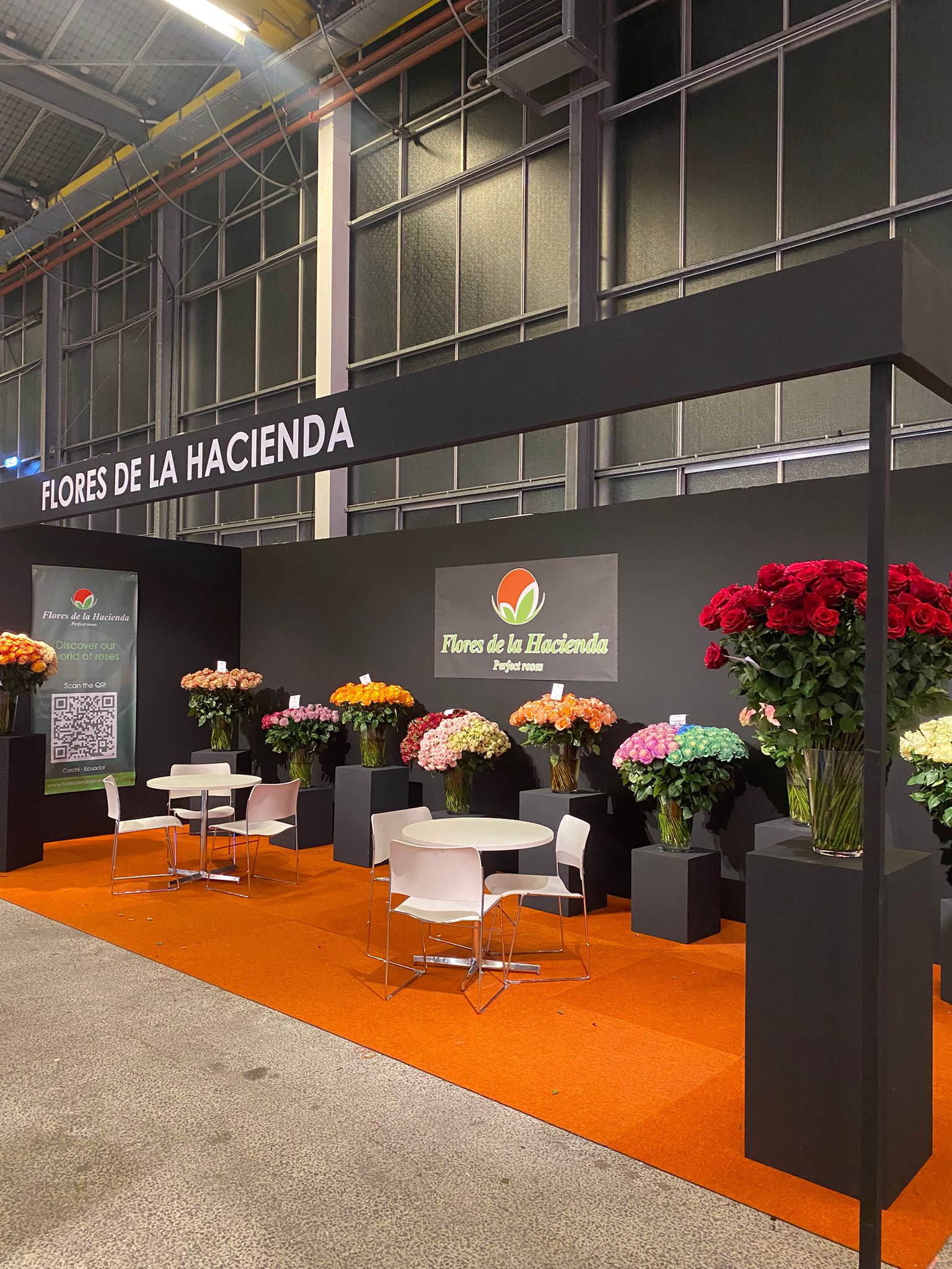 Beursstand met bloemendisplays en witte meubels