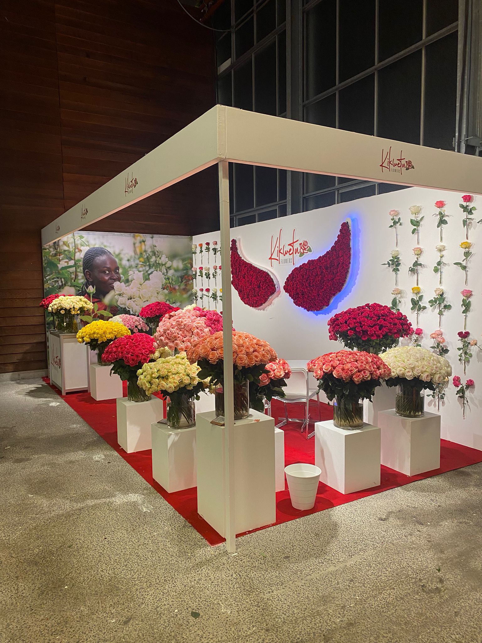 Beursstand met houten vloer, witte meubels en bloemen